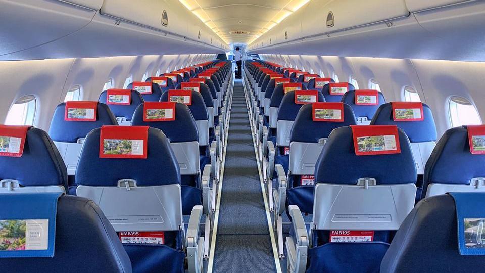 The interior of an empty plane - two rows of navy chairs, two chairs per row.