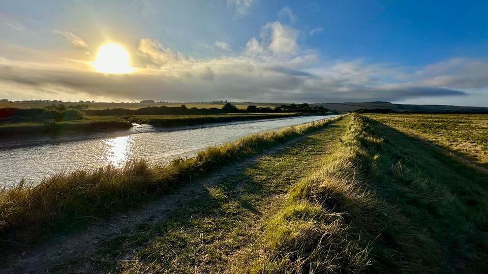 A river running alongside a field.