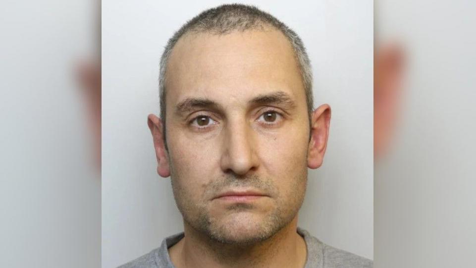 A police head shot of Anthony Snook staring into camera, wearing a grey t-shirt