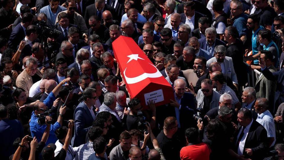 People carry a coffin, covered with a Turkish flag, through the streets