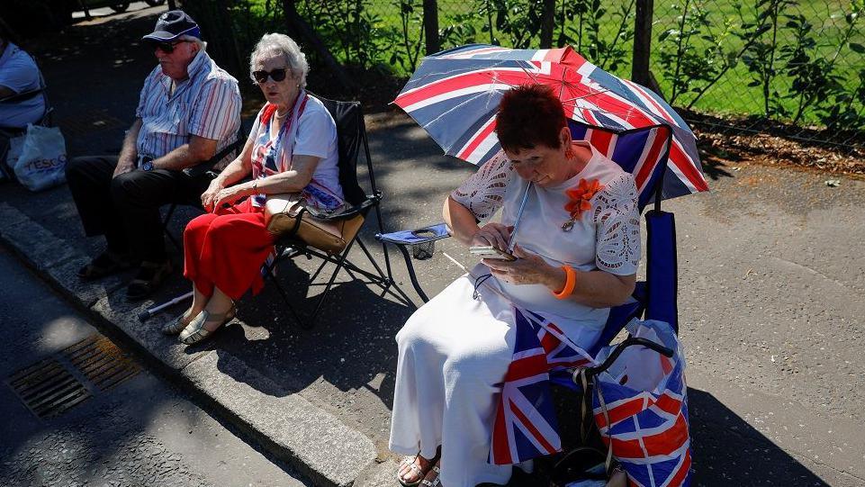 A spectator shading herself from the sun with a union jack umbrella.