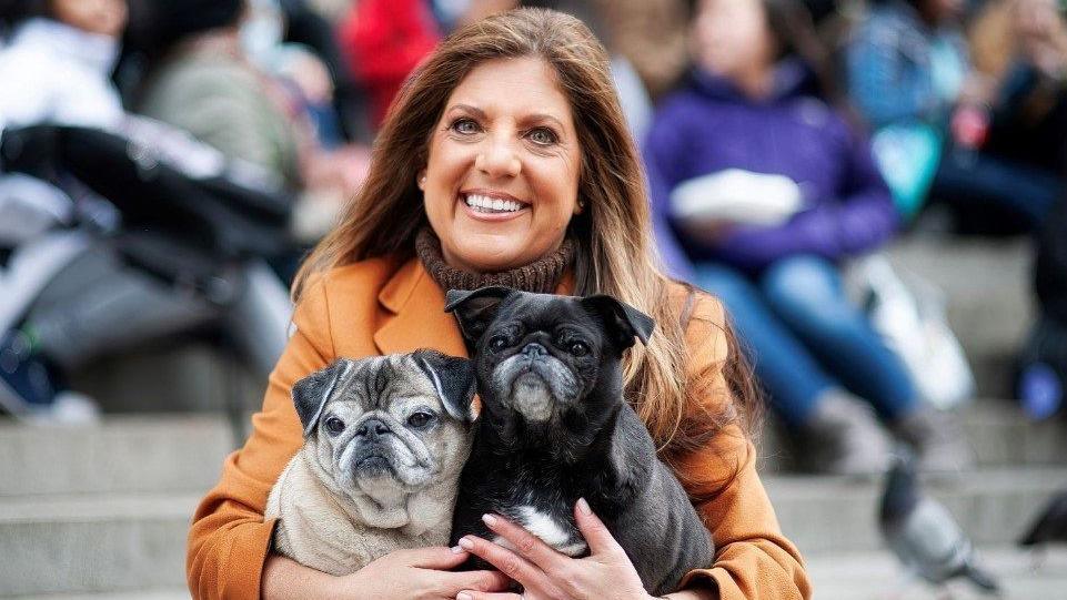 Dr Amy Attas pictured wearing an orange jacket and holding two dogs