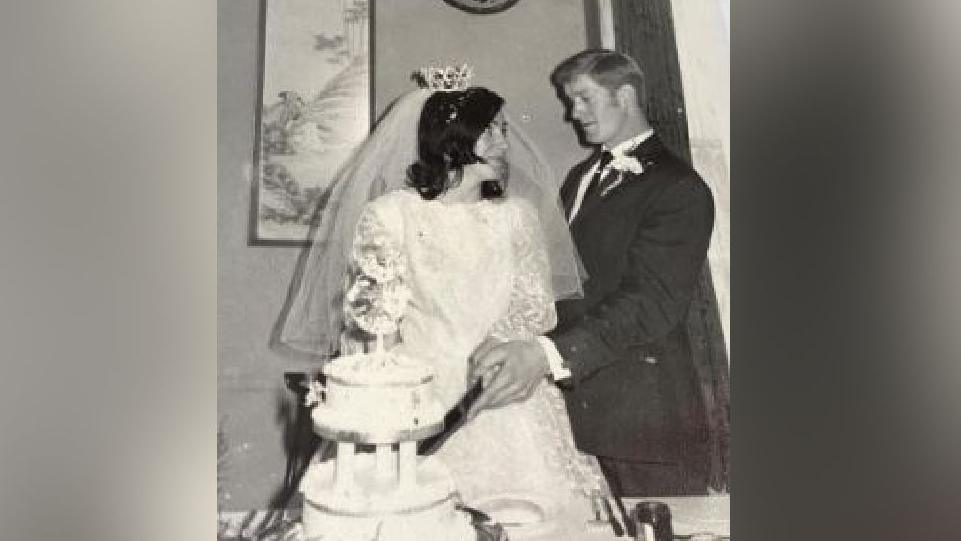 Ceri Ball, left, and husband Glyn pictured on their wedding day. She is wearing a white dress and tiara and he is wearing a dark suit and tie