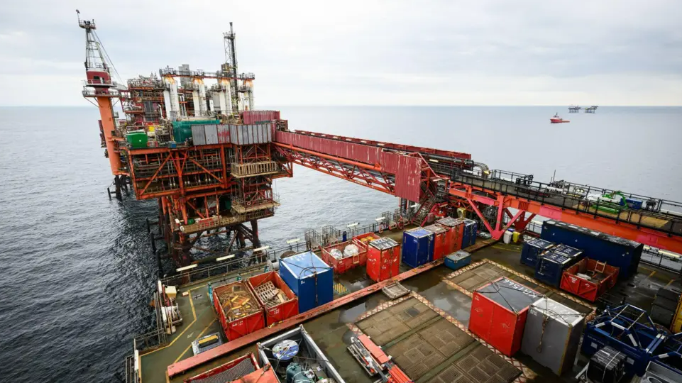 A general view of an oil rig. The structure is mainly red with a number of multi-coloured shipping crates on the deck.