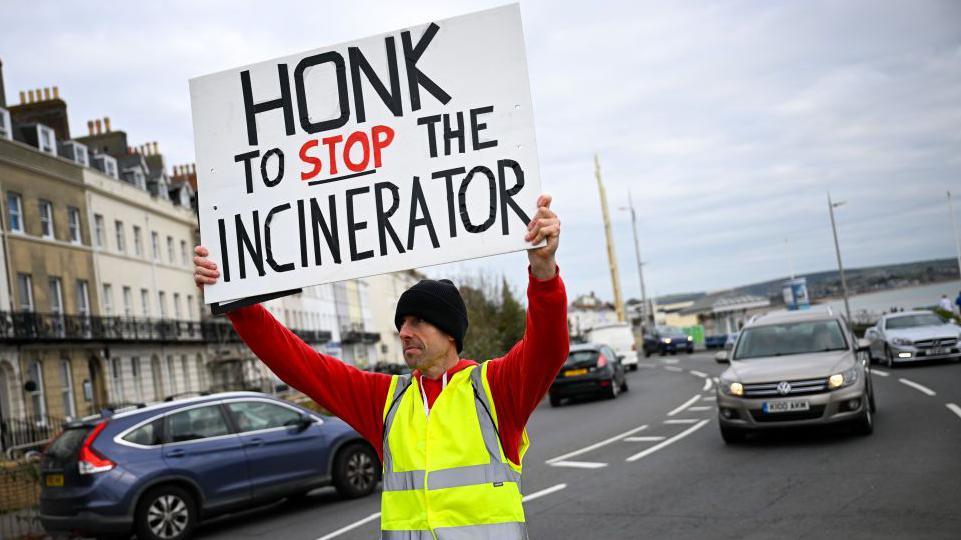 A protestor holds a sign opposing the Portland incinerator in England