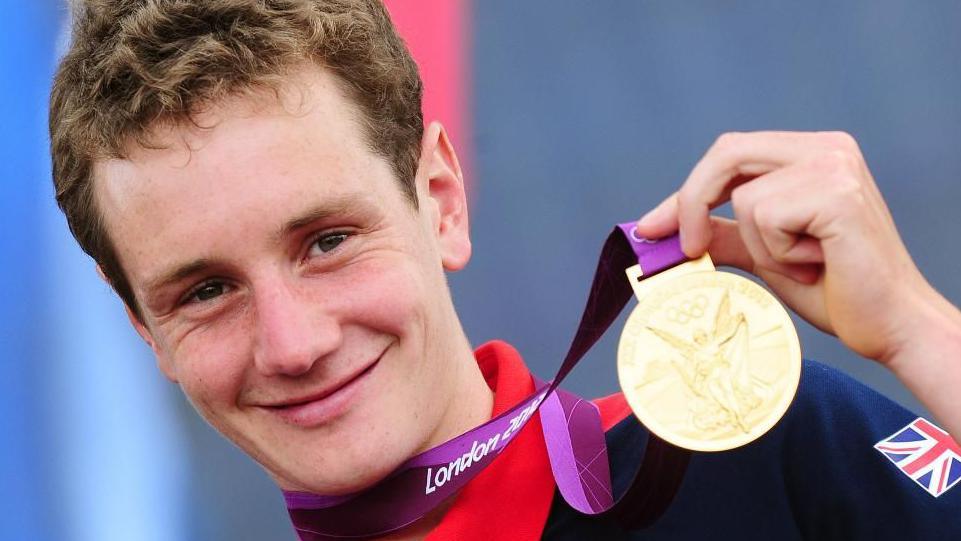 Alistair Brownlee wielding his London 2012 gold medal