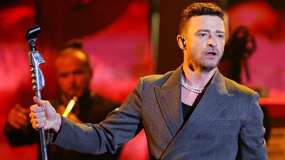 Justin Timberlake performing on stage, holding a microphone stand 