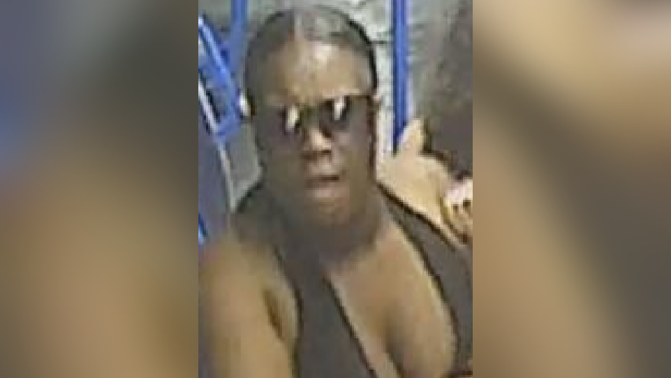 CCTV photo shows a black woman with dark hair, sunglasses and black top.