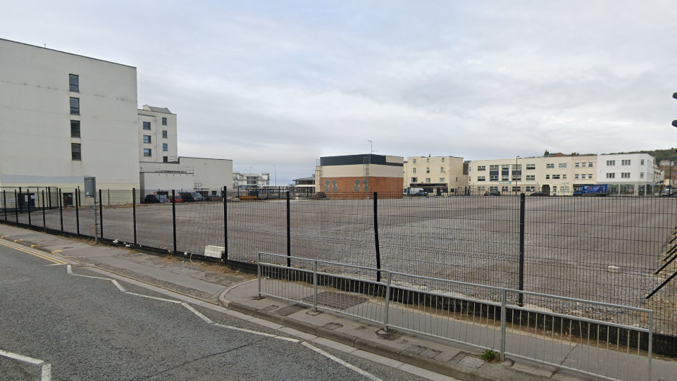 The empty site of Dolphin Square, behind a fence with the road in the foreground