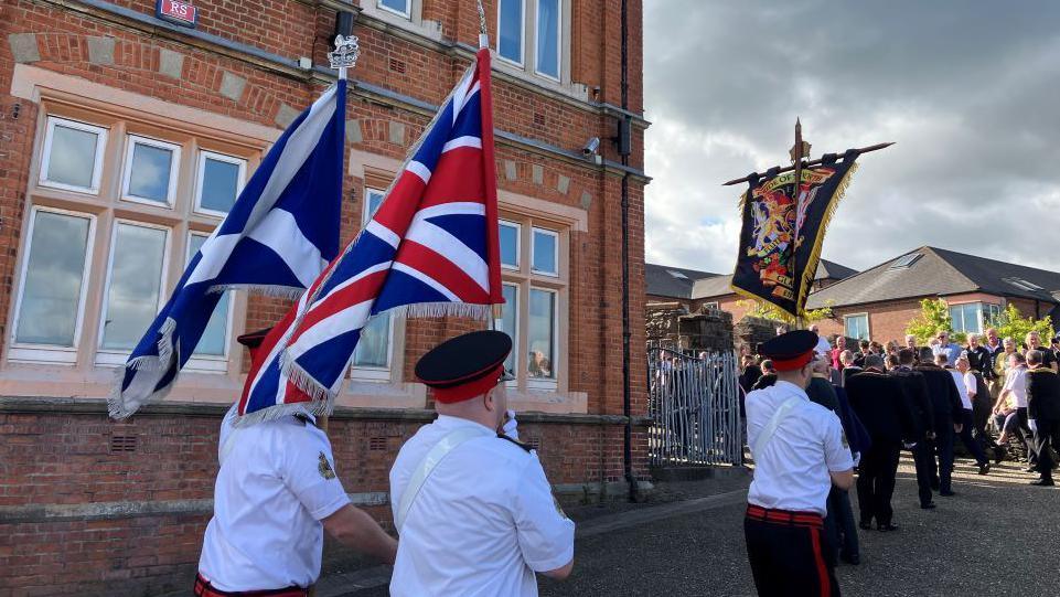 Loyal order members parade the Scottish flag and the union flag with other banners