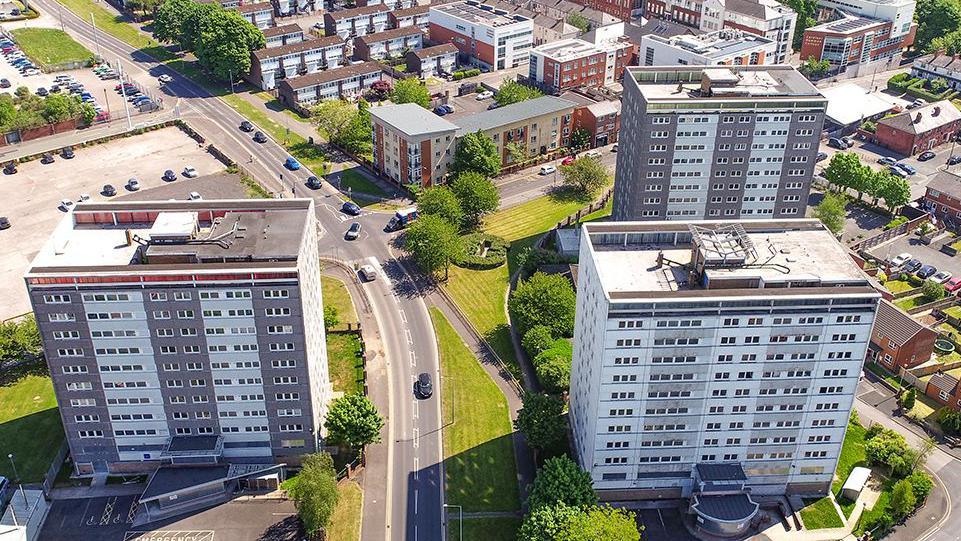 Aerial view of the three Avenham tower blocks, two grey and white clad ones to the right of a road and one to the left