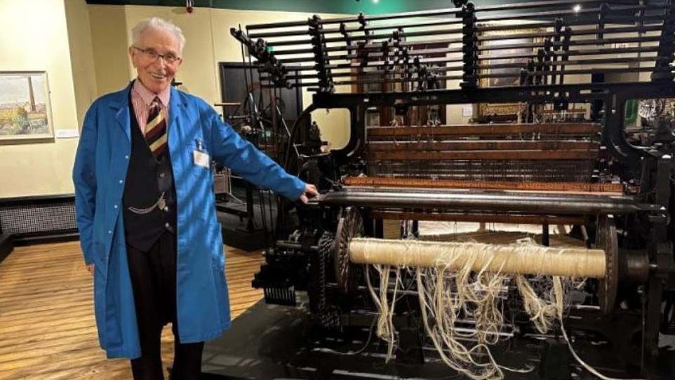 Richard Croasdale standing by a loom inside Blackburn Musuem