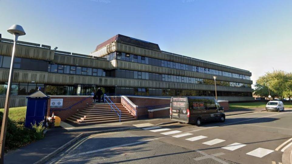 Lincolnshire Police headquarters with several small windows dotted across the building, steps up to the reception, a parking bay and a Doctor Who-style police box outside