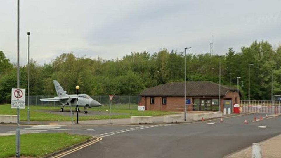 Google Street View image of the outside of RAF Leeming, with a fighter jet to the left-hand side of the entrance.