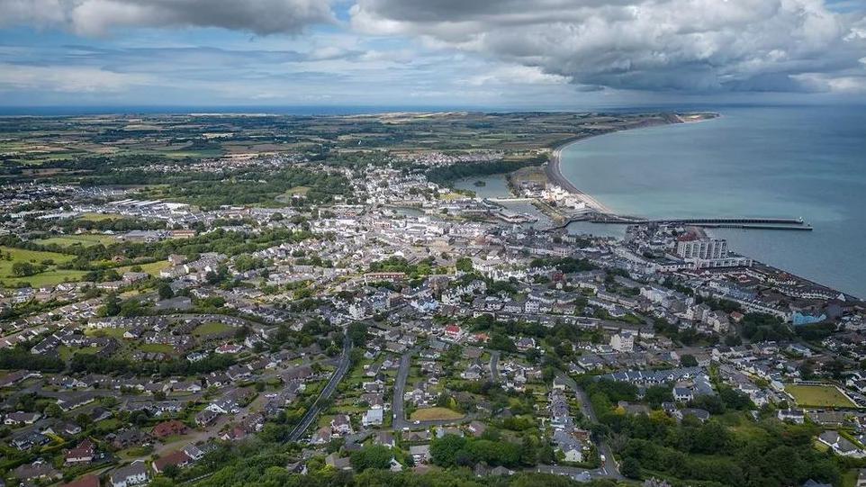 An aerial view of Ramsey showing the roads and houses of the town, which sit close to the sea.