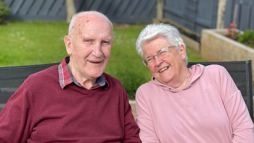 Ken Jack in red jumper and checked shirt, with Eleanor Jack wearing glasses with a pink top