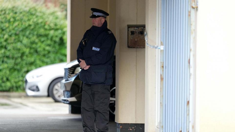 A police officer stood next to a cream outside wall