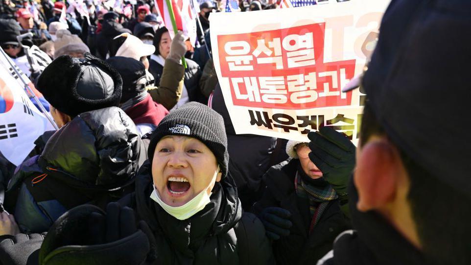 Supporters of impeached South Korean president Yoon Suk Yeol hold placards reading "We will fight with President Yoon Suk Yeol"