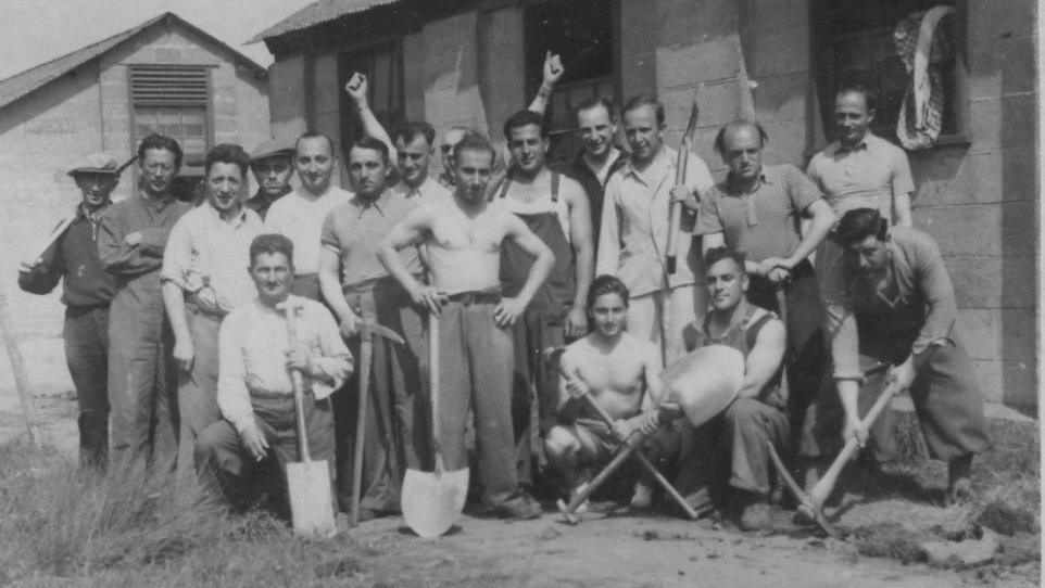 A black and white picture of a group of men with tools including shovels and pick axes.