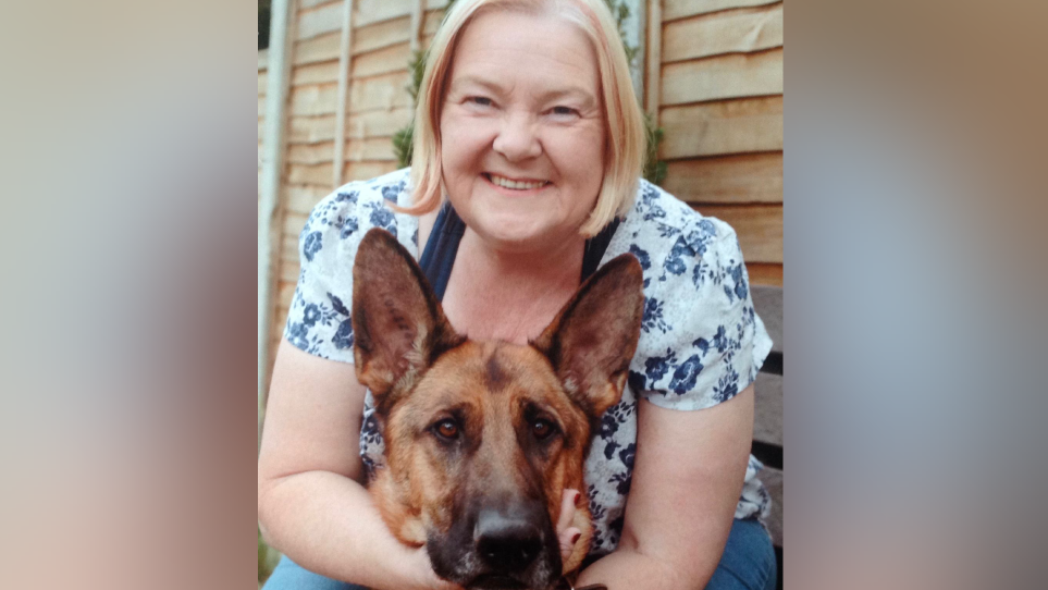 A blonde woman with her arms around a German Shepherd dog.