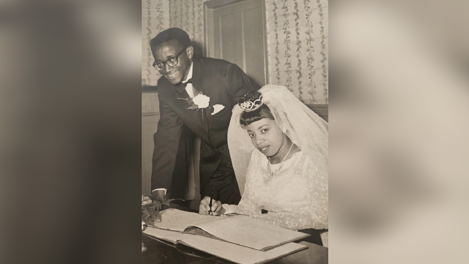 Peter Small and his Eletha Smith wedding photo which Eletha is wearing a tiara that is holding a veil and writing on a document. 