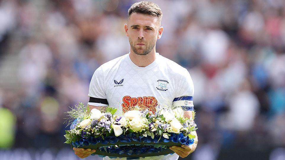 Preston North End's Ben Whiteman presents a floral wreath on the pitch in memory of Liverpool player Diogo Jota ahead of the pre-season friendly