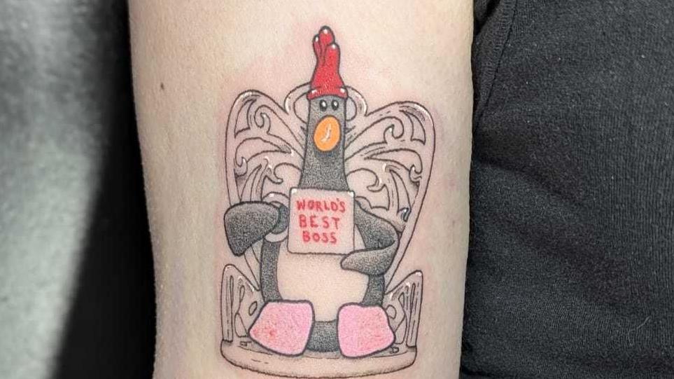 tattoo of Feathers with his trademark red rubber glove hat and holding a mug saying "world's best boss".