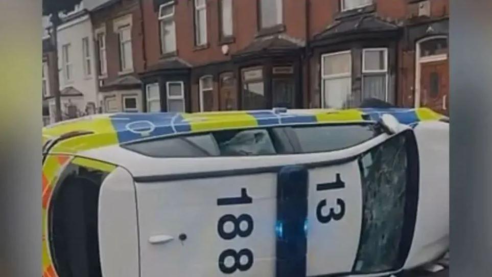 A police car is overturned in a street 