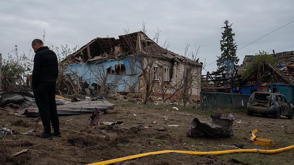 A man stands amid debris in front of residential houses destroyed by Russian shelling on May 6, 2025 in Velyka Chernechchyna, Sumy Oblast