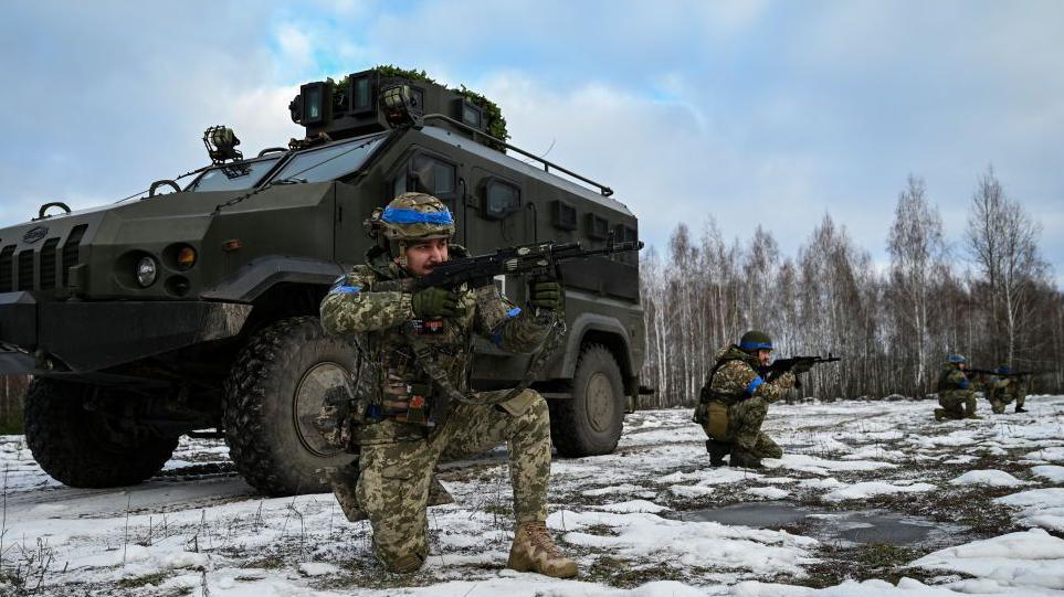 Soldiers aim their weapons into distance. 