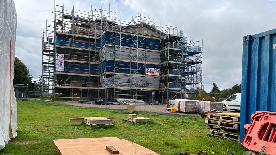 A Borders mansion surrounded by scaffolding, work vans and wooden pallets.