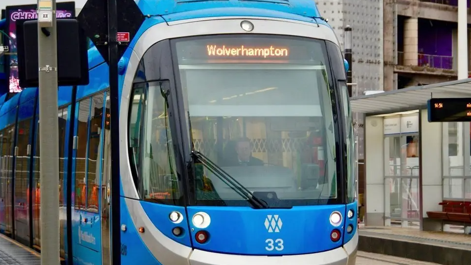 A tram with a Wolverhampton sign lit up above the driving compartment sits at a stop