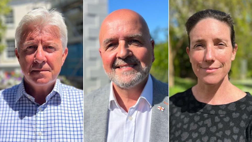 Three people look towards the camera in sunny weather.
On the left is Deputy Mark Helyar, who is wearing a blue and white checked shirt and has grey hair.
In the middle, is Deputy Jonathan Le Tocq, who's bald and has a grey beard. He's wearing a grey suit with a Guernsey flag pin on the lapel.
Pictured right is Deputy Lindsay de Sausmarez. She's wearing a black blouse with grey hearts on.