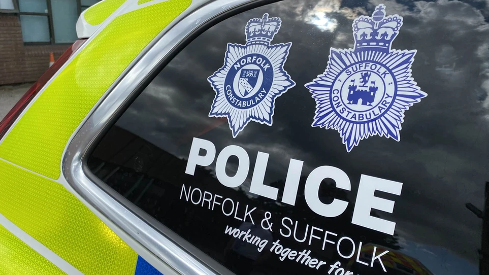 A close-up shot of the Norfolk and Suffolk police emblems on a police car window