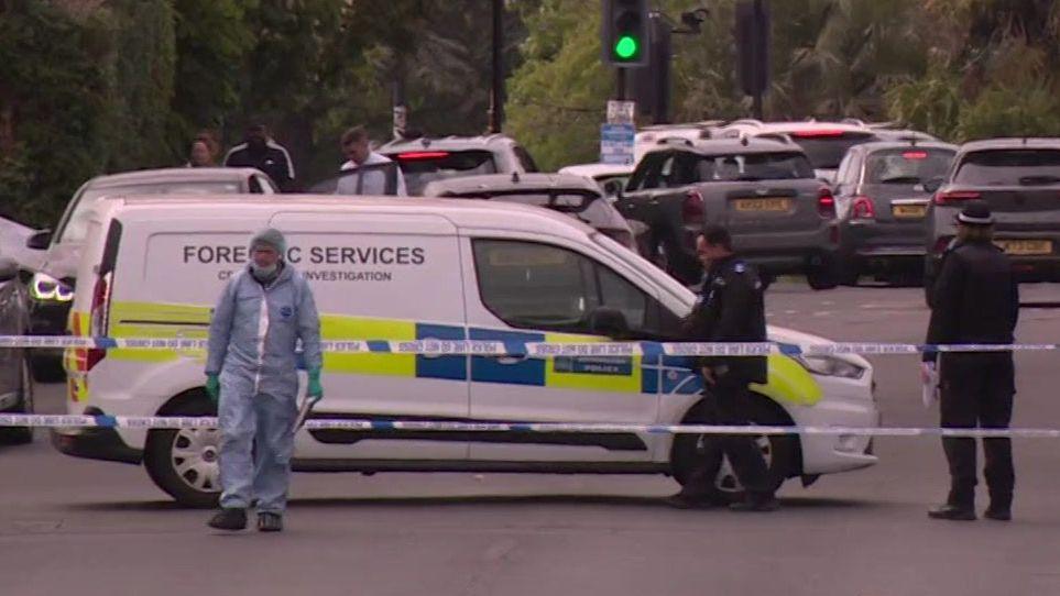 A forensic van and police officers on Kingsbury Road behind police tape