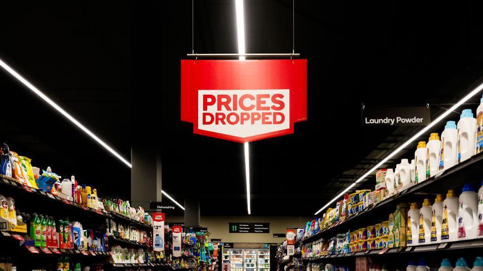 A supermarket aisle with a prices dropped sign.