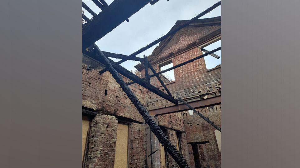Bare bricks and burned wooden beams inside Woolton Hall