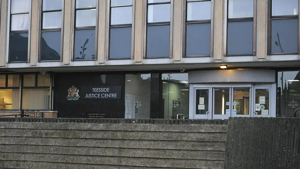 Exterior of the grey-concrete court building. A sign next to the glass doors reads: "Teesside Justice Centre".