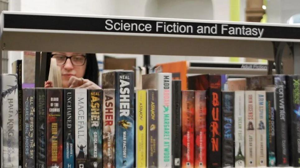 A woman looking at books on a shelf in a library