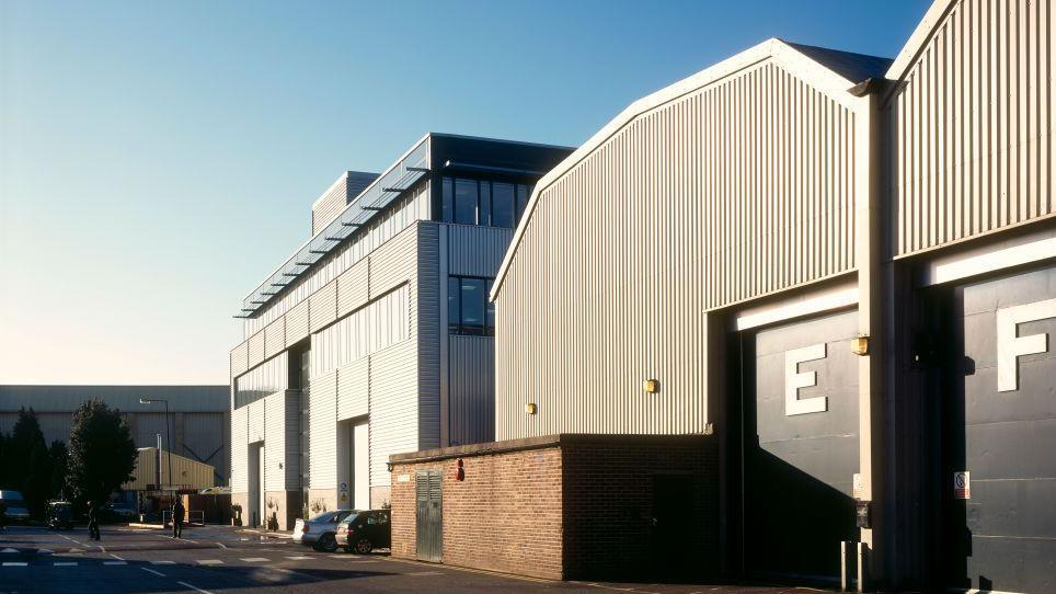 A film lot, which has two large stage buildings to the side and a further one at the end of the road.