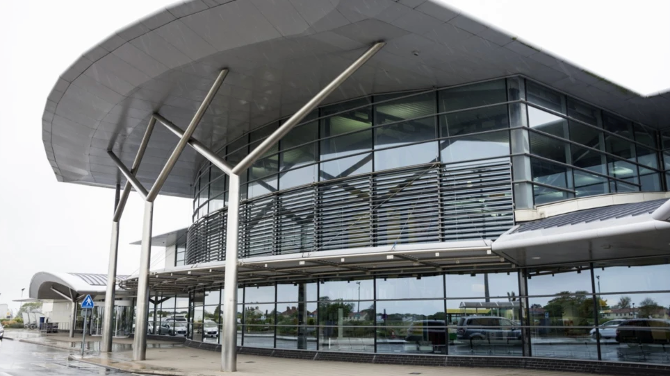 The outside of Guernsey Airport arrivals terminal on a grey skied day.