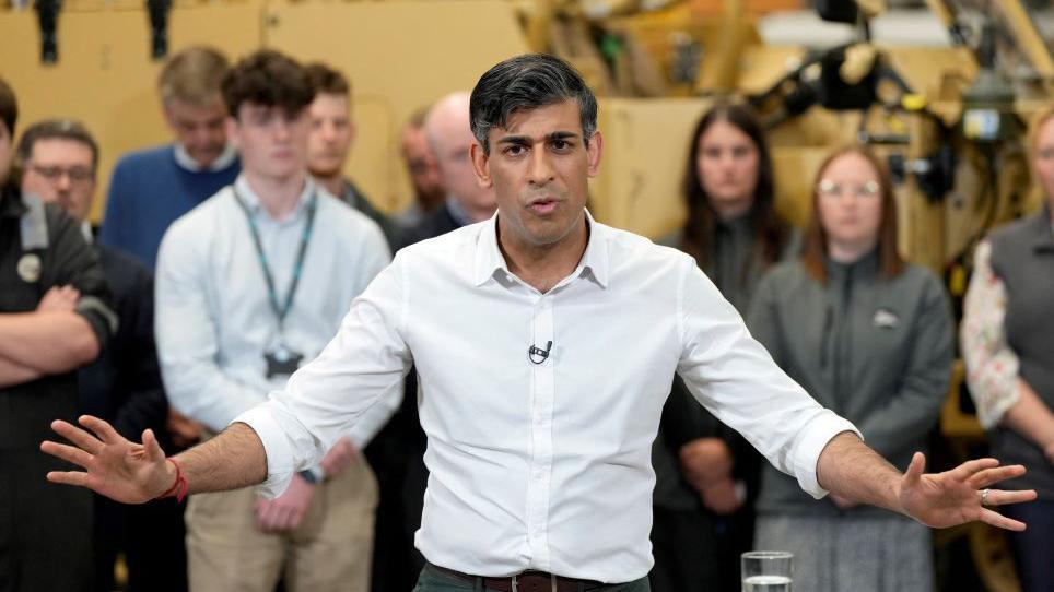 Rishi Sunak gesturing with his arms open wide as he answers questions at an event in Devon