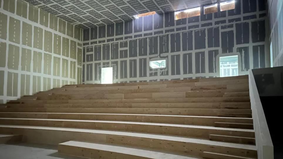 Wooden steps in a large room that is under construction with plaster panels on the wall