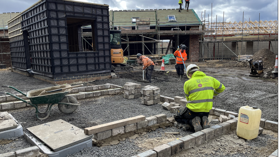 A building site with a man laying bricks in the foreground 