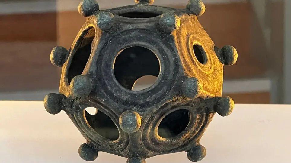 A metal dodecahedron dating from the Roman times, it has cut out circles in the metalwork as well as small round balls of metal all over.  