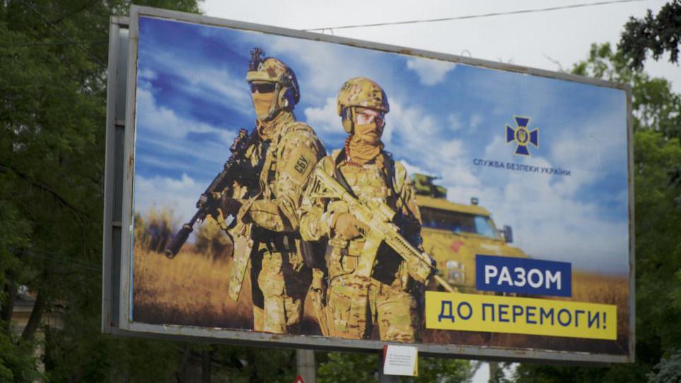 Military poster shows two soldiers standing with guns in arms