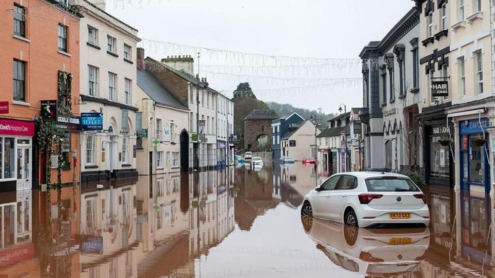 Cars stuck in flood water in a high street.