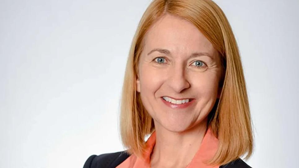 Katy Bourne smiling at the camera in front of a white background. 