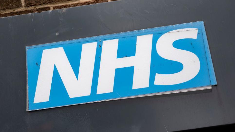 The blue and white NHS logo. 