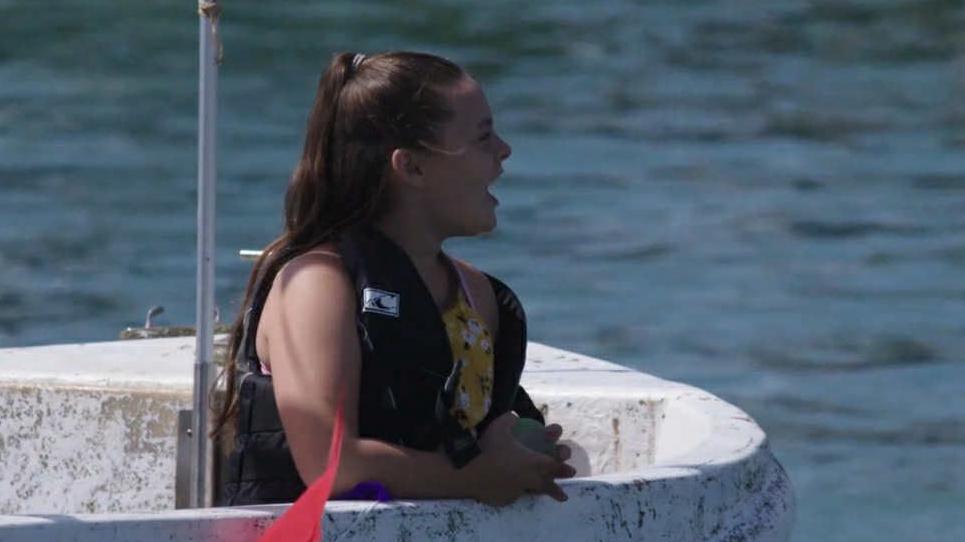 Alisha Ponter sits on a small boat wearing a life jacket while looking across the water. The sea and part of the vessel are visible around her.